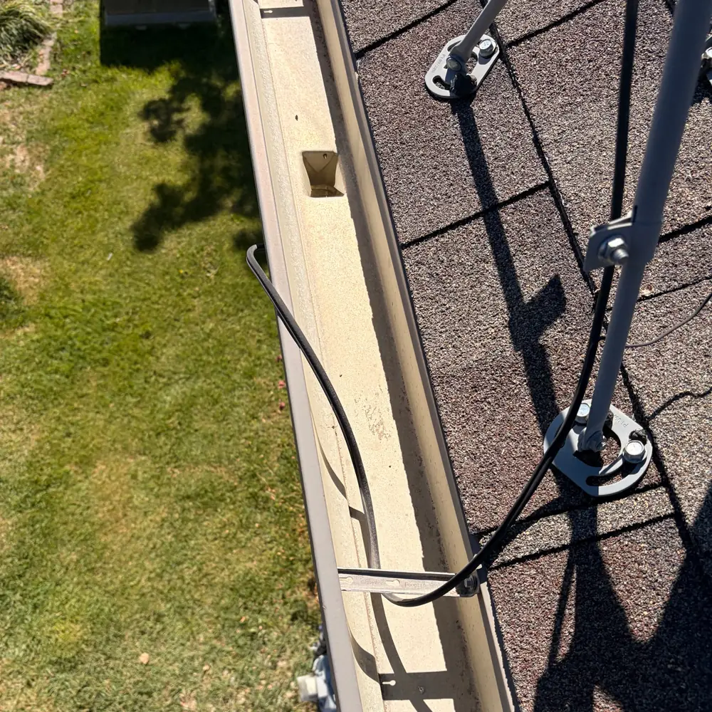 Clean gutter and downspout outlet beside a satellite dish mount after gutter cleaning