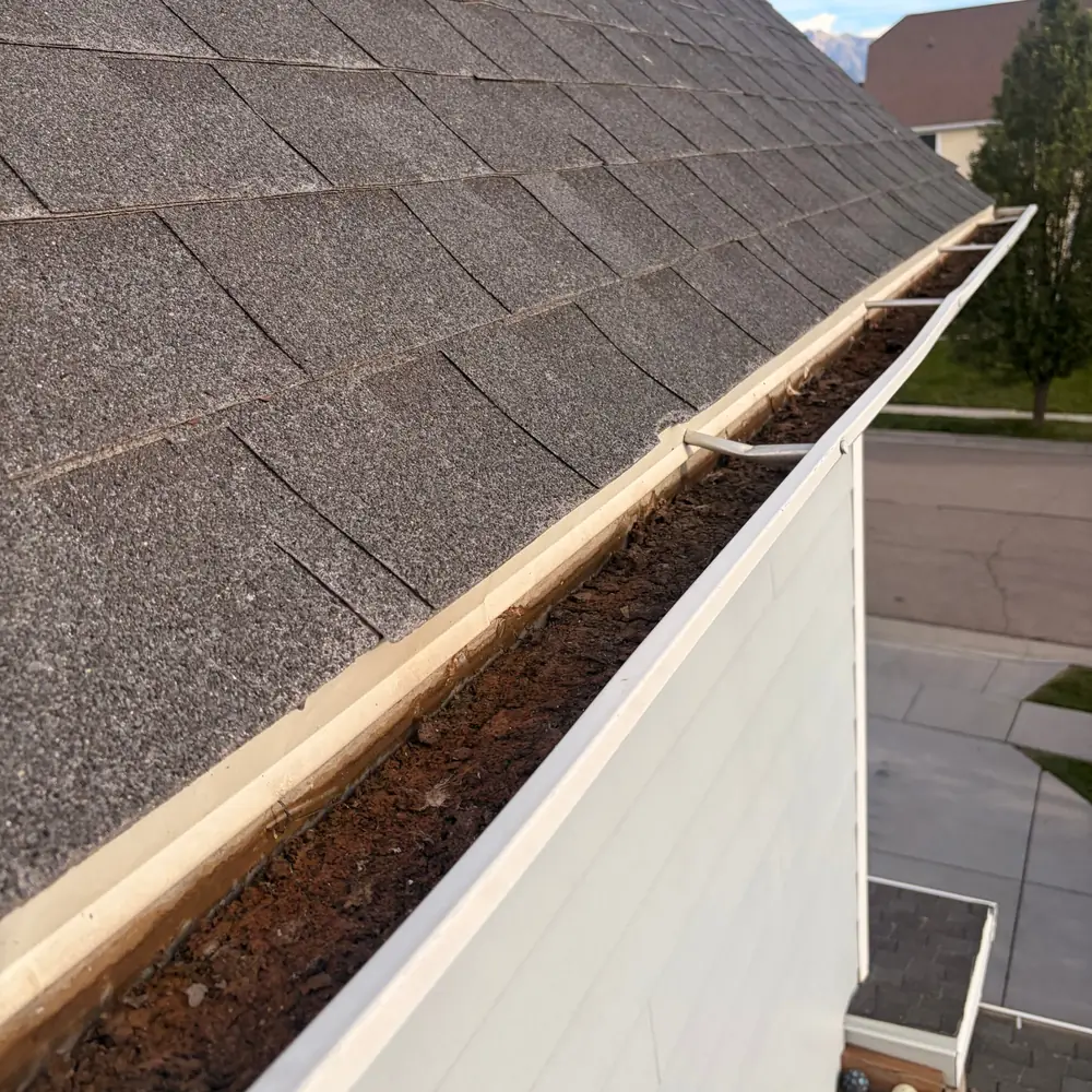 Gutter packed with leaves and sludge before professional gutter cleaning in Utah