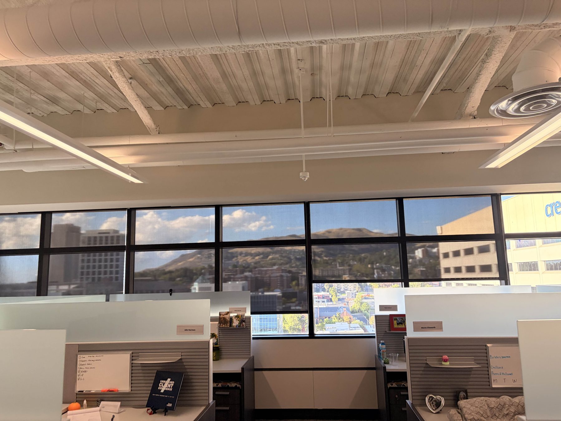 Streak-free interior office window cleaning, downtown Salt Lake City high-rise — wide window wall over an open-plan floor looking out to the city and the Wasatch foothills