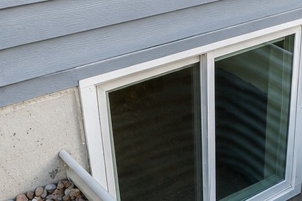 Clean basement window glass and drainage rock after window well cleaning in Salt Lake City